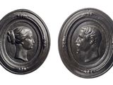 two silver medallions of a man and a woman in profile