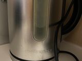 a silver kettle sitting on a counter with a black cord