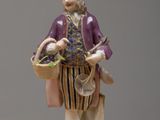 a figurine of a man with a basket of flowers