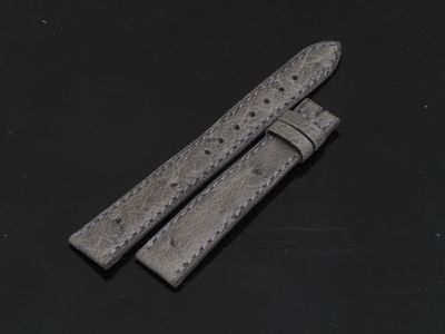 une paire de bracelets de montre en cuir gris posés sur une surface noire