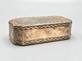an old silver box sitting on top of a table next to a white wall