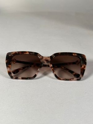 des lunettes de soleil de couleur marron tortue posées sur une surface blanche