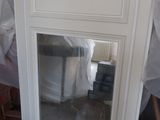 a mirror in the corner of a fireplace with a gold decoration on it