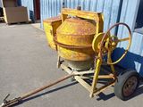 a yellow cement mixer sitting on a cart in front of a building