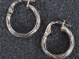 deux paires de boucles d'oreilles créoles en argent posées sur une surface noire