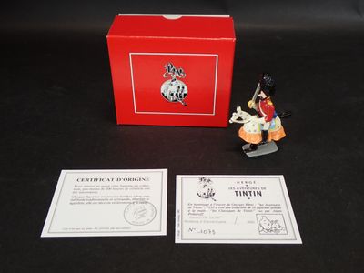 La figurine est posée à côté d'une boîte rouge sur une table noire.