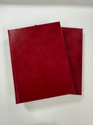 two red notebooks sitting on top of each other on a white surface