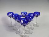 six blue wine glasses are lined up in a row on a white surface