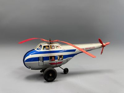 un hélicoptère miniature posé sur une surface grise, avec un fond gris
