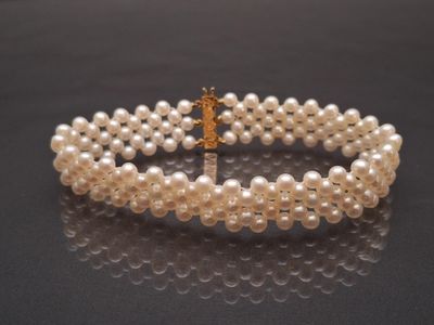 two rows of white pearls with a gold clasp on a black surface