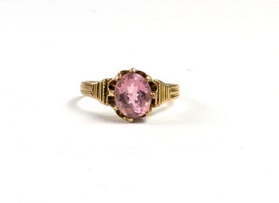 gros plan d'une bague en pierre rose sur une surface blanche