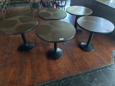 trois tables et quatre tabourets posés sur un parquet dans un restaurant
