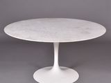 une table en marbre blanc avec un piètement circulaire sur fond gris