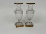 une paire de vases en cristal taillé reposant sur des socles en bois, sur fond blanc
