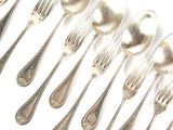 un grand nombre de cuillères et de fourchettes en argent sur une surface blanche