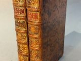two old books sitting on top of each other on a table