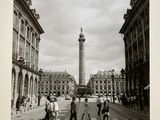 photographie en noir et blanc montrant des personnes traversant la rue devant une tour horloge