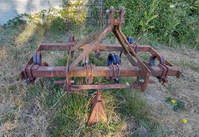 une charrue rouillée posée dans l'herbe au bord de l'eau
