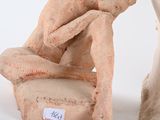 a statue of a man sitting on a chair next to a vase