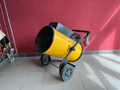 a yellow cement mixer sitting on the floor next to a red wall