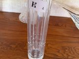 un vase en verre transparent posé sur une table, avec une étiquette portant un nom