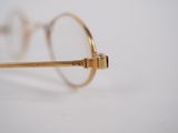gold rimmed glasses on a white surface with a white background