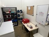une petite pièce avec un bureau et un tableau blanc accroché au mur