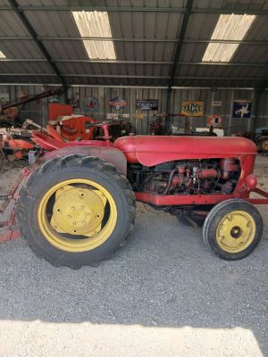 un tracteur rouge et jaune garé dans un garage