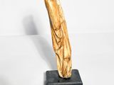 a wooden sculpture on a black stand on a white surface
