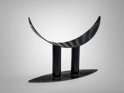 a metal sculpture of a curved object on a stand