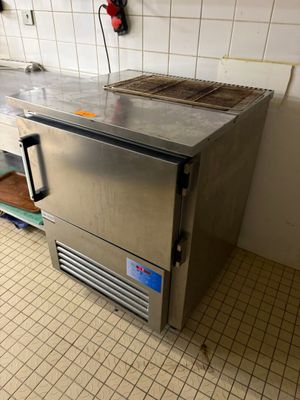 un plan de travail en acier inoxydable dans une cuisine au sol carrelé