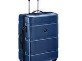 La valise bleue repose sur ses roulettes, posée sur une surface blanche.