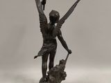 a bronze statue of an angel holding a bird on a rock