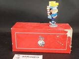 une petite figurine posée sur une boîte rouge