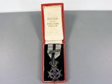 an image of a silver medal with a purple ribbon in a red box