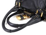 a black purse with gold hardware on the strap