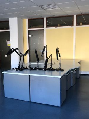 cinq bureaux dans une pièce, sur lesquels sont posées trois lampes