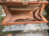 a brown suitcase sitting on a rock in the woods