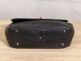a black leather purse sitting on top of a wooden table