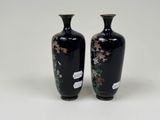 pair of black vases with floral designs on them on a white surface