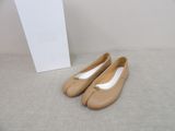 une paire de chaussures beiges posée sur une boîte blanche