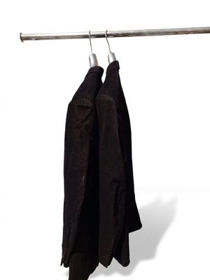 two jackets hanging on a clothes rack on a white wall