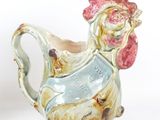 a small ceramic chicken shaped pitcher on a white surface