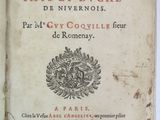 un vieux livre posé sur une table à côté d'une table blanche