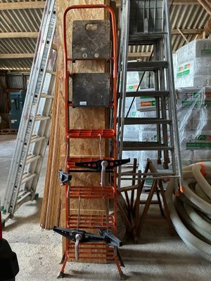 un homme assis sur une chaise à côté d'une pile d'échelles