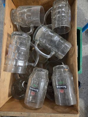 une caisse remplie de chopes de bière vides posée par terre