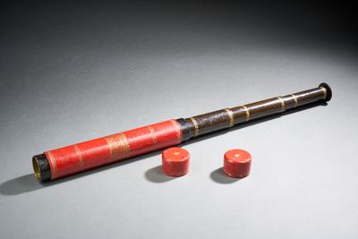 un vieux télescope avec un étui rouge et deux boutons rouges
