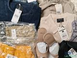 a pile of clothes and a pair of sandals on a bed