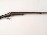 un vieux pistolet avec une crosse en bois accroché à un mur blanc