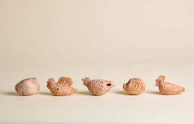 Plusieurs petits animaux en argile sont alignés sur une surface blanche